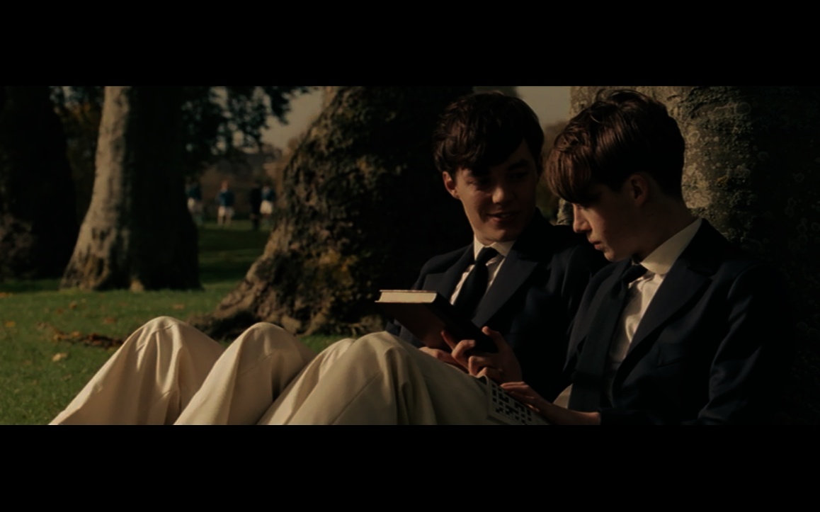 Der junge Alan Turing sitzt neben seinem Jugendfreund Christopher unter einem Baum, sie unterhalten sich. 
